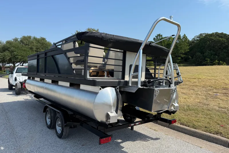 Slide: The Image of 2025 Flagship E22RF Sport Toon pontoon boat on trailer, parked on roadside. - 10