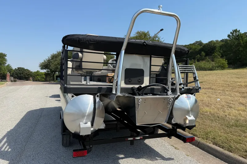 Slide: The Image of 2025 Flagship E22RF Sport Toon pontoon boat on a trailer, parked on a sunny road. - 13