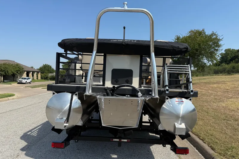 Slide: The Image of 2025 Flagship E22RF Sport Toon pontoon boat on trailer, parked on suburban street. - 14