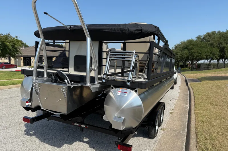 Slide: The Image of 2025 Flagship E22RF Sport Toon pontoon boat on trailer, parked on a suburban street. - 15