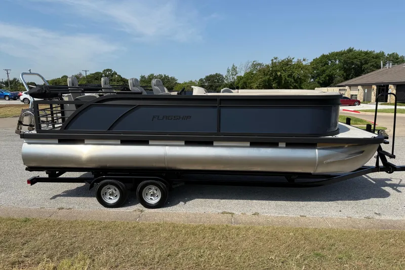 Slide: The Image of 2025 Flagship E22RF Sport Toon pontoon boat on trailer, parked on roadside. - 19