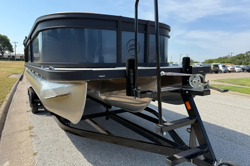Slide: The Image of 2025 Flagship E22RF Sport Toon pontoon boat on trailer, parked on a sunny street. - 23