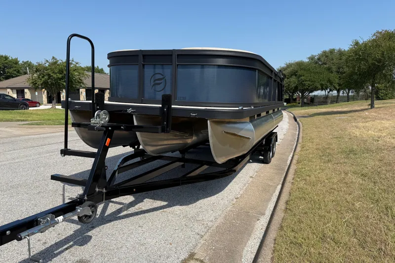 Slide: The Image of 2025 Flagship E22RF Sport Toon pontoon boat on trailer, parked on suburban street. - 34
