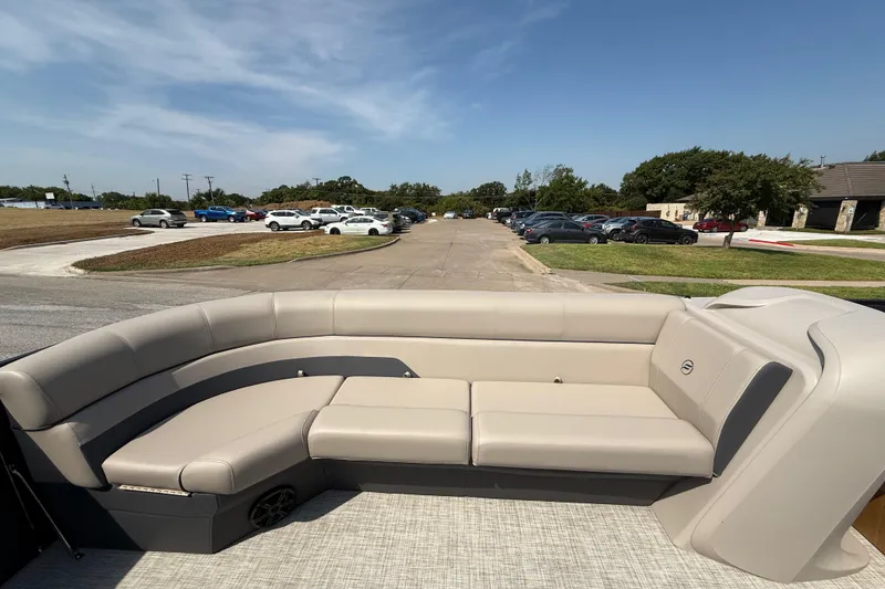 Slide: The Image of 2025 Flagship E22RF Sport Toon boat with beige seating, parked near a lot. - 42