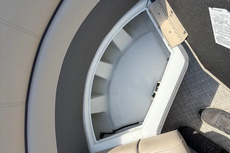 Slide: The Image of Storage compartment in 2025 Flagship E22RF Sport Toon boat, featuring beige upholstery and gray flooring. - 47