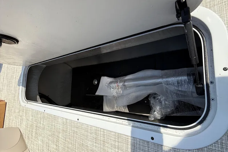 Slide: The Image of Storage compartment of 2025 Flagship E22RF Sport Toon boat, open with wrapped items inside. - 57