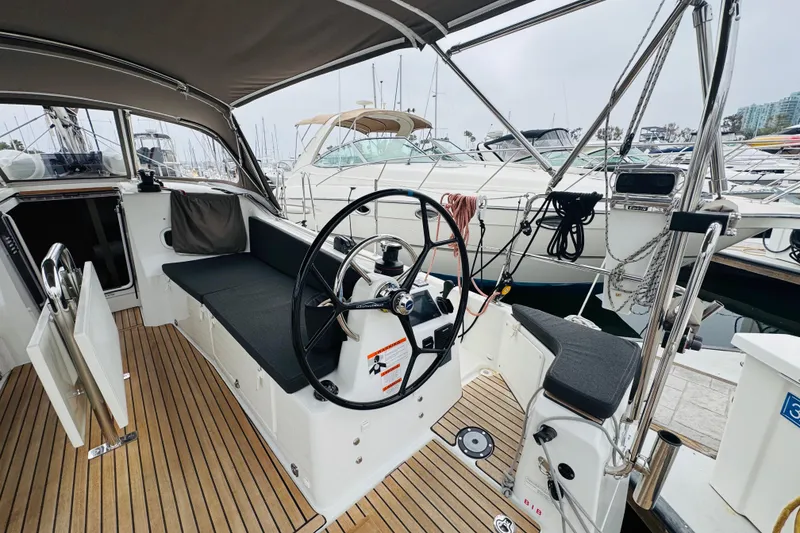 Slide: The Image of 2023 Jeanneau 380 sailboat cockpit with steering wheel, seating, and marina view. - 11