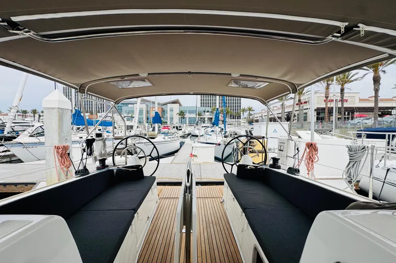 Slide: The Image of 2023 Jeanneau 380 yacht cockpit view at marina, showcasing dual steering wheels and seating. - 12