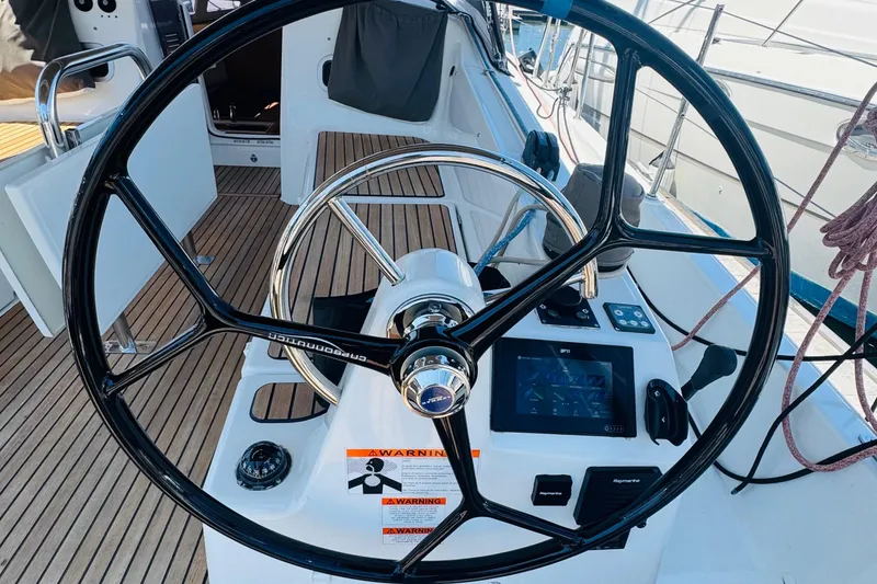 Slide: The Image of Steering wheel and controls of 2023 Jeanneau 380 sailboat, featuring modern navigation equipment. - 14