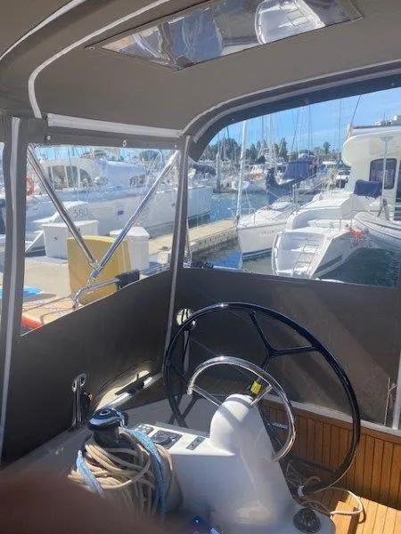 Slide: The Image of 2023 Jeanneau 380 yacht helm with marina view, showcasing steering wheel and nautical equipment. - 27