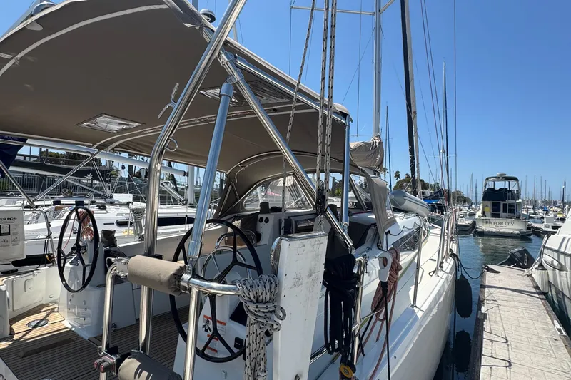 Slide: The Image of 2023 Jeanneau 380 sailboat docked at marina, featuring dual steering wheels and sunshade. - 33