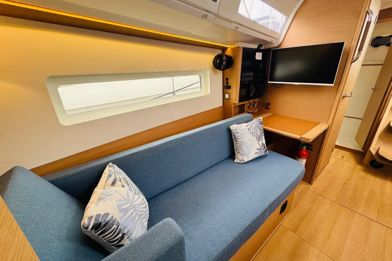 Slide: The Image of Modern Jeanneau 380 yacht interior with blue sofa, TV, and wooden accents, 2023 model. - 50