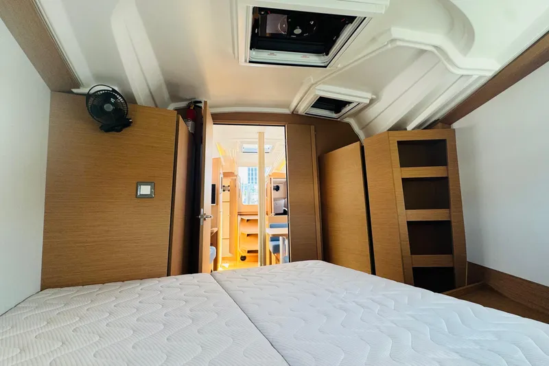 Slide: The Image of 2023 Jeanneau 380 interior cabin with bed, wooden shelves, and ceiling hatch. - 58