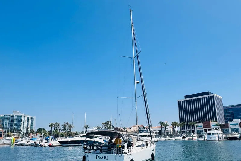 Slide: The Image of 2023 Jeanneau 380 sailboat docked in a marina with cityscape background. - 68