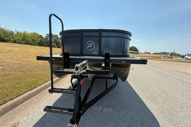Slide: The Image of 2025 Flagship F22CU SPORT TOON pontoon boat on a trailer, parked on a sunny road. - 2