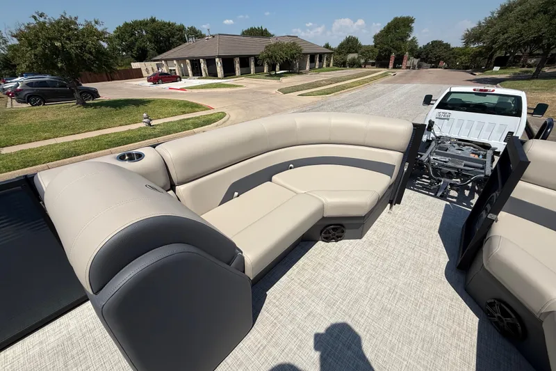 Slide: The Image of 2025 Flagship F22CU SPORT TOON boat interior with beige seating, parked in a suburban area. - 27