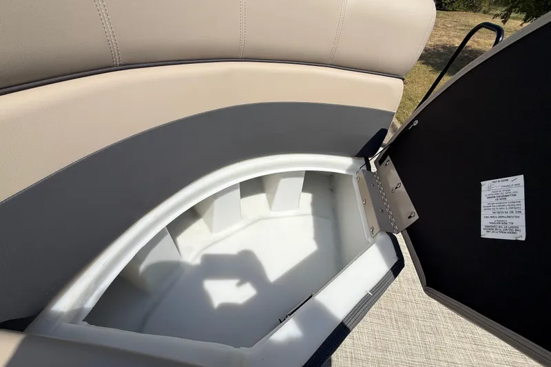 Slide: The Image of Open storage compartment in 2025 Flagship F22CU SPORT TOON boat, featuring beige and gray seating. - 31