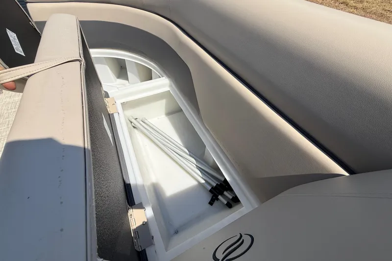 Slide: The Image of 2025 Flagship F22CU SPORT TOON boat storage compartment with beige seating and metal poles. - 36