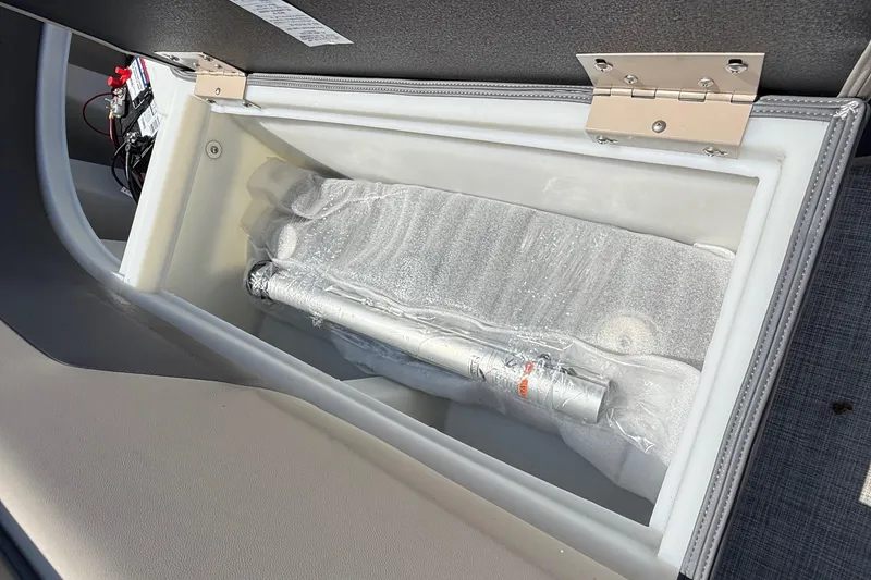 Slide: The Image of Open storage compartment in 2025 Flagship F22CU SPORT TOON boat, showing battery and wrapped items. - 58