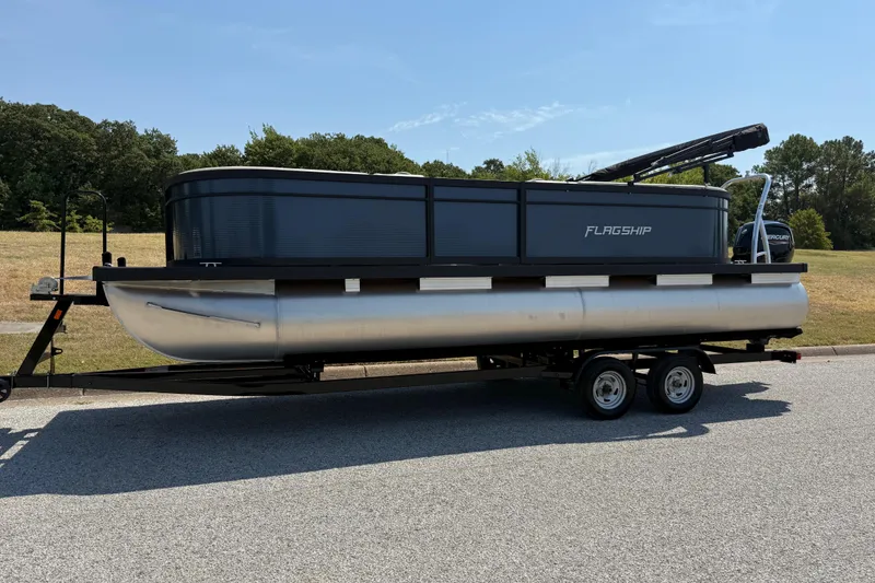 Slide: The Image of 2025 Flagship F22CU SPORT TOON pontoon boat on trailer, parked outdoors. - 6