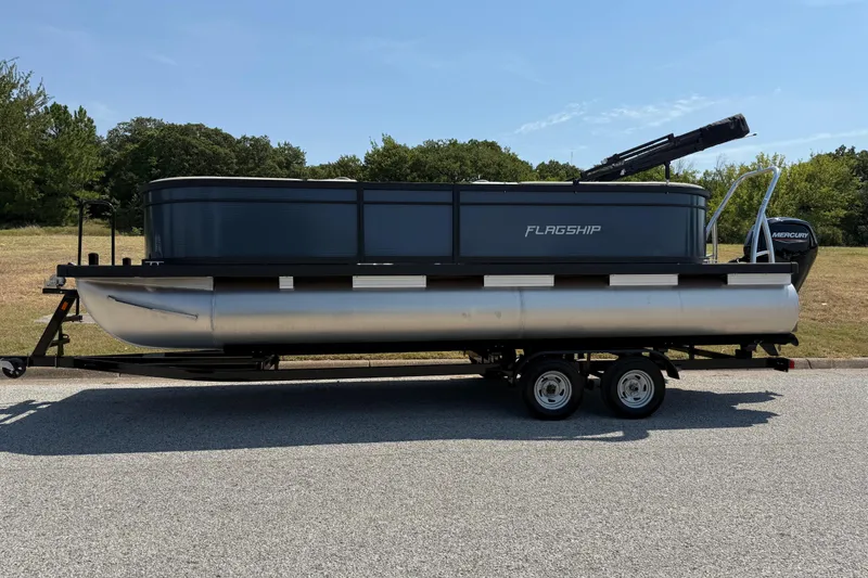 Slide: The Image of 2025 Flagship F22CU SPORT TOON pontoon boat on trailer, parked outdoors. - 7