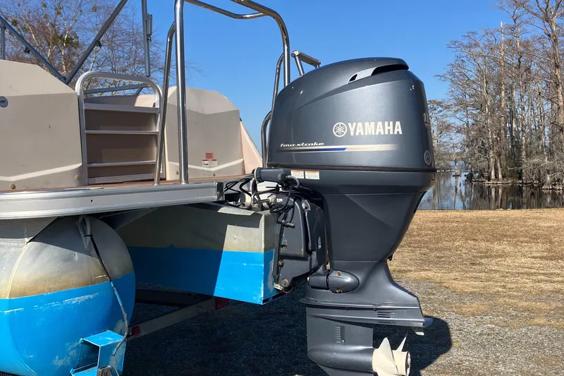 Slide: The Image of 2013 South Bay 724 pontoon boat with Yamaha outboard motor, near a serene lake. - 7