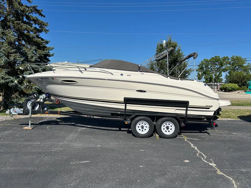 Slide: The Image of 2004 Sea Ray 225 Weekender boat on trailer, parked outdoors under clear blue sky. - 0