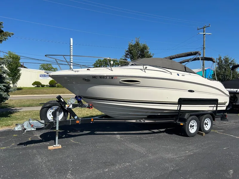 Slide: The Image of 2004 Sea Ray 225 Weekender boat on trailer, parked outdoors under clear blue sky. - 1