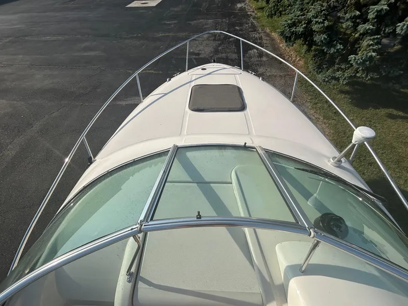 Slide: The Image of 2004 Sea Ray 225 Weekender boat deck with windshield and railing, parked on pavement. - 12