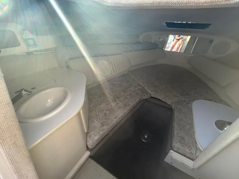 Slide: The Image of 2004 Sea Ray 225 Weekender cabin interior with bed and sink, illuminated by sunlight. - 19