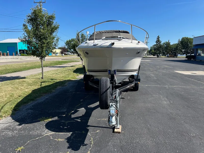 Slide: The Image of 2004 Sea Ray 225 Weekender boat on trailer, parked on asphalt under clear blue sky. - 2