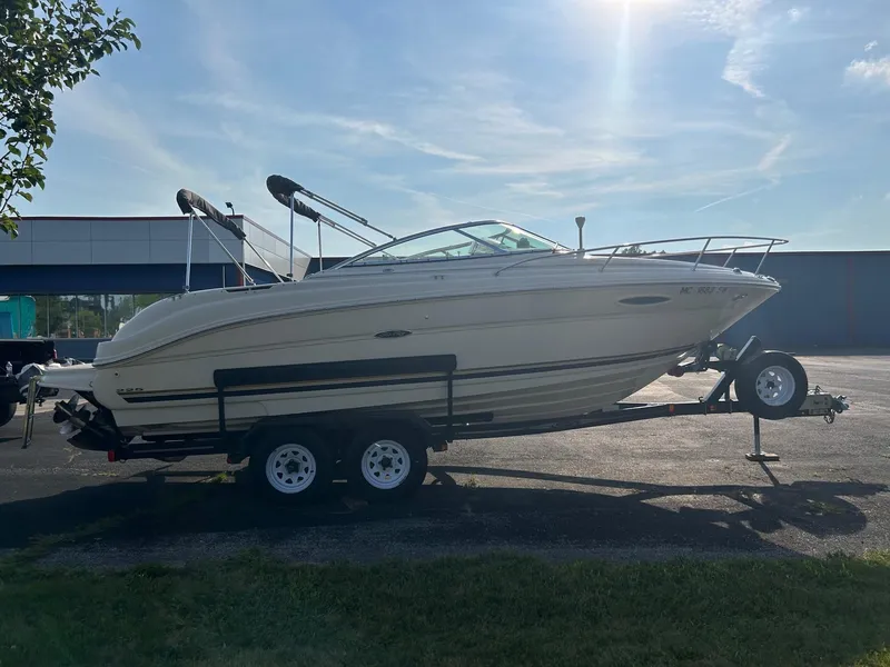 Slide: The Image of 2004 Sea Ray 225 Weekender boat on trailer, parked outdoors under clear sky. - 28