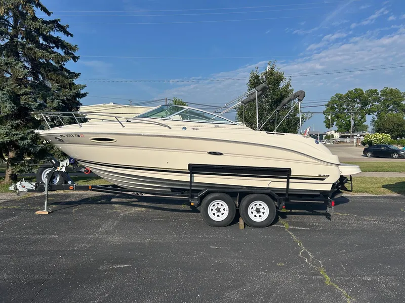Slide: The Image of 2004 Sea Ray 225 Weekender boat on trailer, parked outdoors under clear sky. - 29