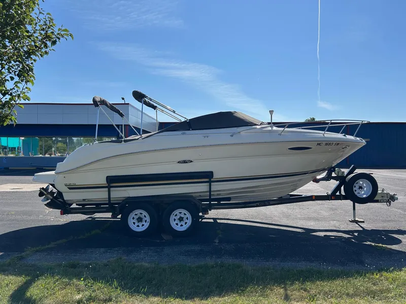 Slide: The Image of 2004 Sea Ray 225 Weekender boat on trailer, parked outdoors under clear blue sky. - 4
