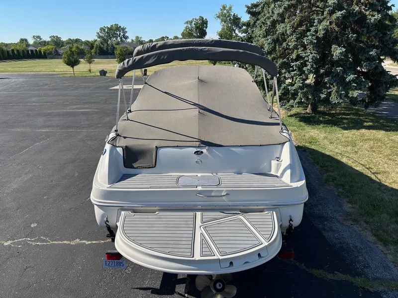 Slide: The Image of 2004 Sea Ray 225 Weekender boat with canopy, parked on asphalt near trees. - 7