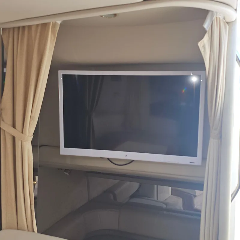 Slide: The Image of Flat-screen TV inside a 2000 Formula 31 PC boat cabin with beige curtains. - 24