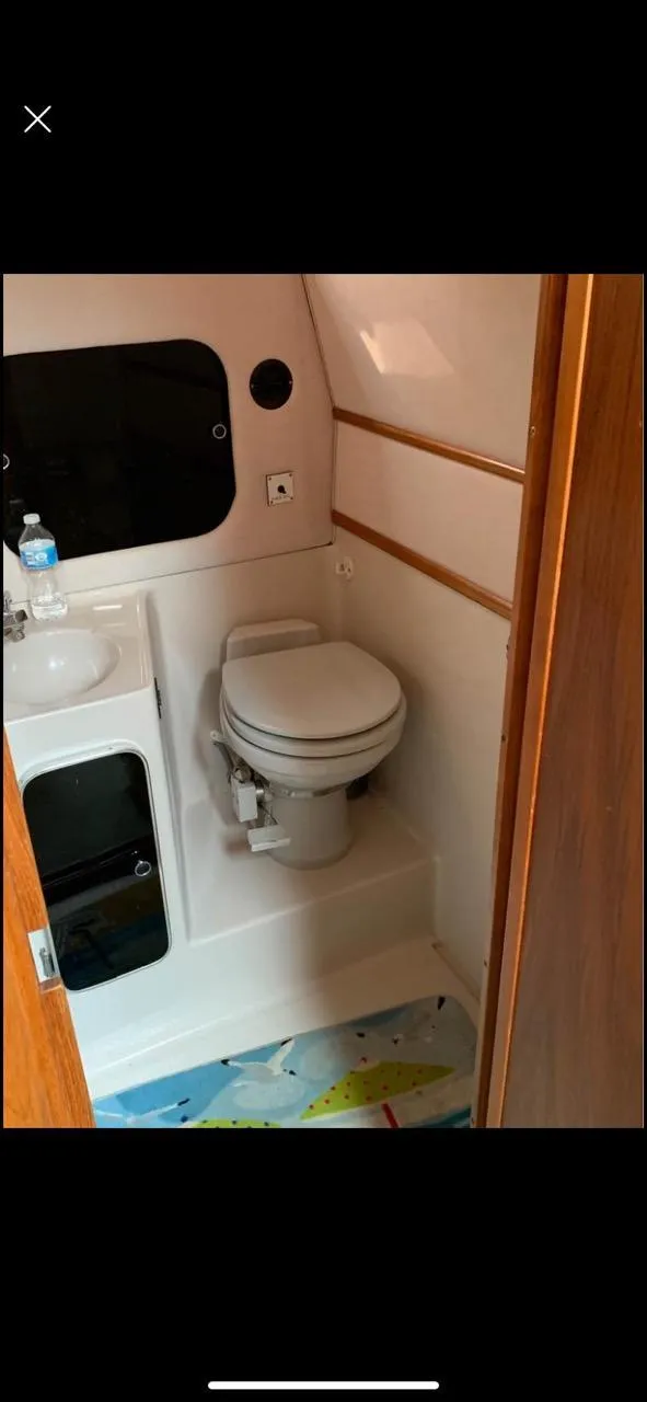 Slide: The Image of 1987 Sea Ray 36 Sundancer bathroom with toilet, sink, and wooden accents. - 12