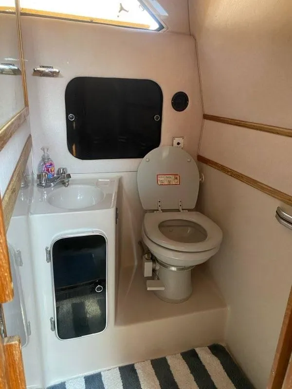 Slide: The Image of 1987 Sea Ray 36 Sundancer bathroom with sink, toilet, and window. - 13