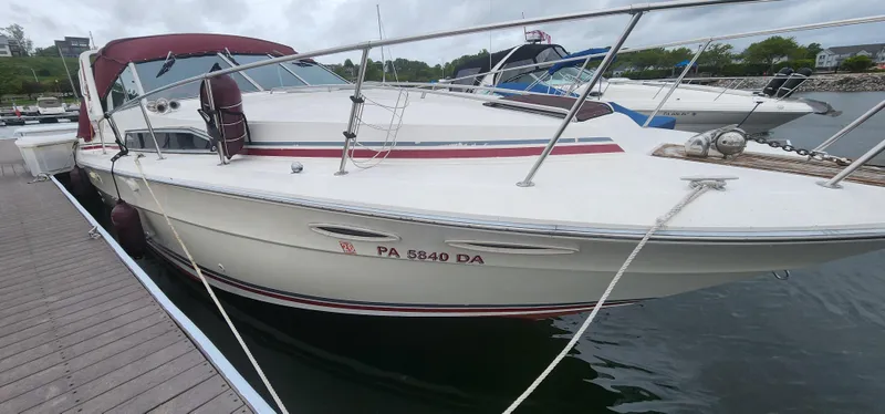 Slide: The Image of 1987 Sea Ray 36 Sundancer docked at marina, featuring sleek design and maroon accents. - 38