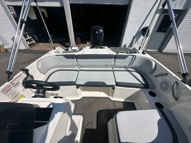Slide: The Image of 2022 Bayliner Element M17 boat interior with seating and steering wheel, docked near a garage. - 10