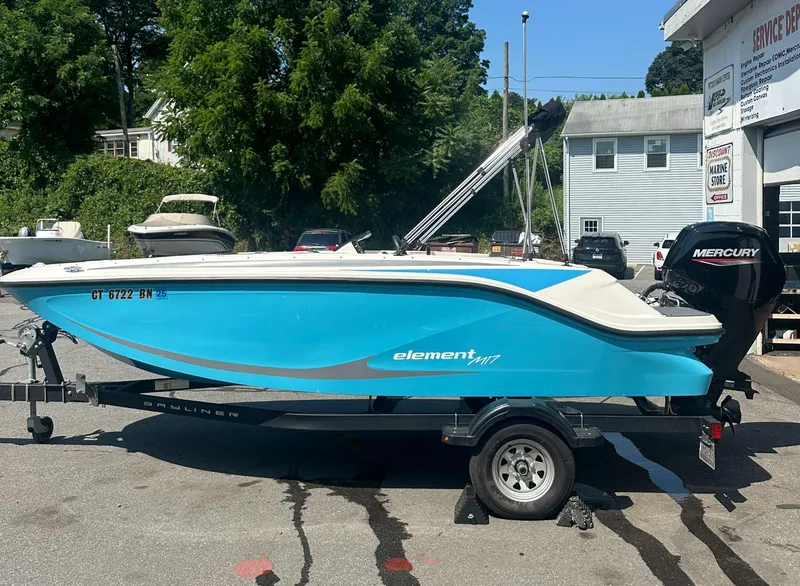 Slide: The Image of 2022 Bayliner Element M17 boat on trailer, blue hull, parked outdoors. - 4