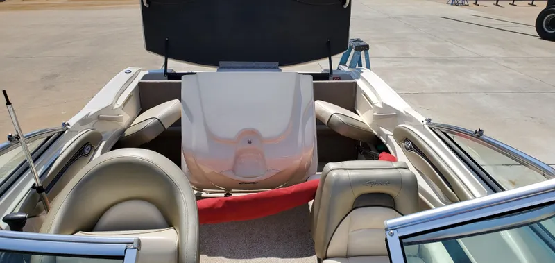 Slide: The Image of 2005 Sea Ray 200 Sport boat interior with open engine compartment, beige seating, and red safety equipment. - 13
