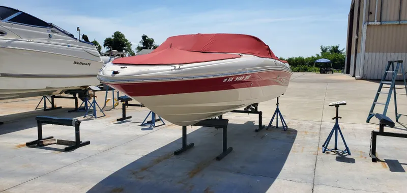 Slide: The Image of 2005 Sea Ray 200 Sport boat with red cover on stands, parked outdoors. - 3