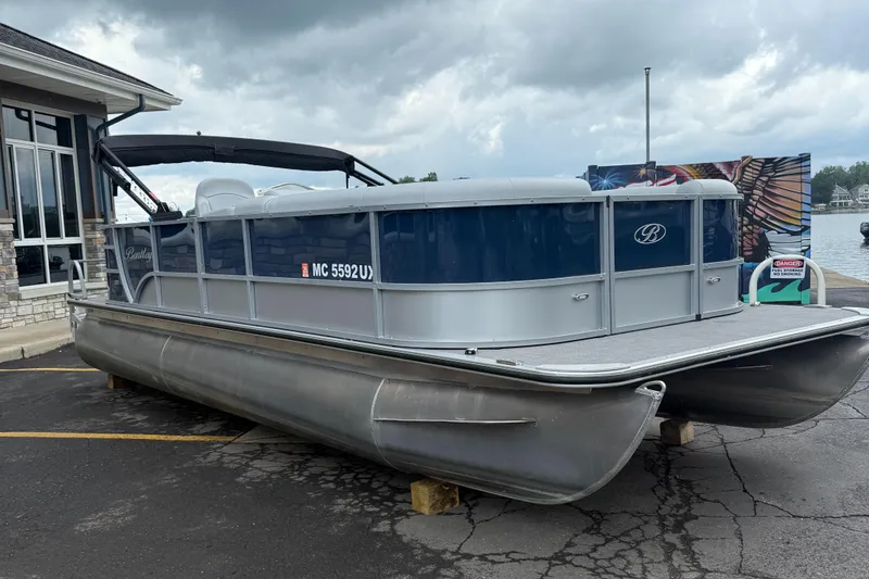 Slide: The Image of 2022 Bentley Pontoons 220CR boat on display near a waterfront, under cloudy skies. - 2