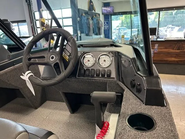 Slide: The Image of 2026 Lund 1650 Angler Sport boat interior with steering wheel and dashboard controls. - 2