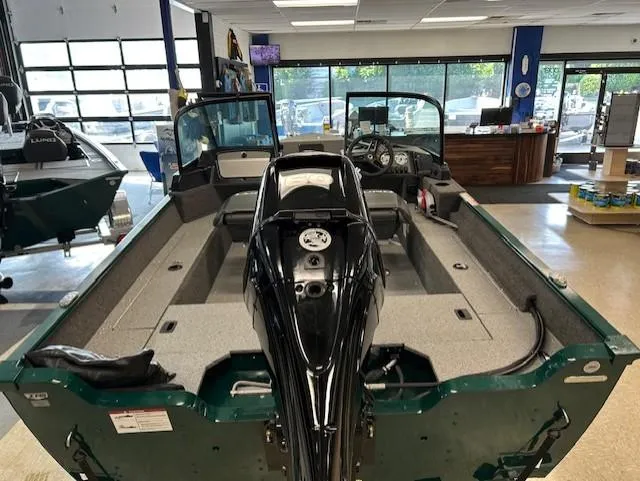 Slide: The Image of 2026 Lund 1650 Angler Sport boat interior in showroom, featuring motor and seating. - 4