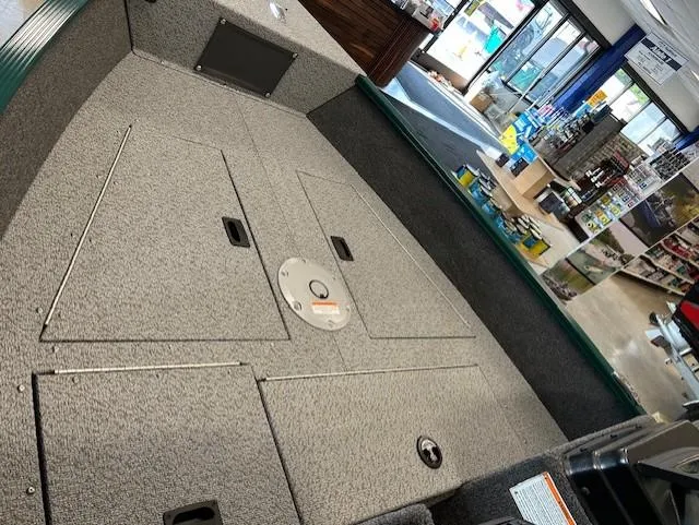 Slide: The Image of 2026 Lund 1650 Angler Sport boat interior with storage compartments in a showroom. - 7