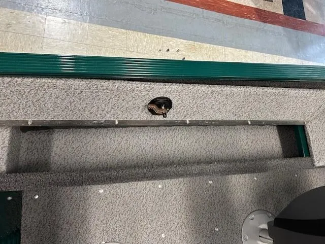 Slide: The Image of 2026 Lund 1650 Angler Sport boat interior with textured flooring and green trim. - 9