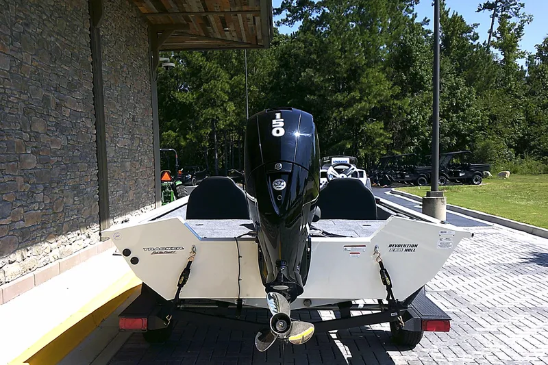 Slide: The Image of 2025 Tracker Pro Team 195 Tournament Edition boat with 150 HP engine, parked outdoors. - 2