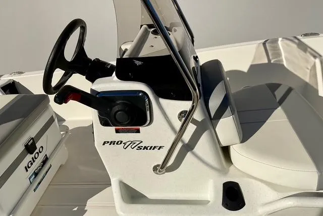 Slide: The Image of 2025 Mako Pro Skiff 17 CC boat console with steering wheel and Igloo cooler. - 16